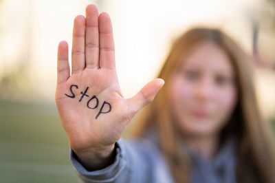 Frau hält Handfläche nach vorn, auf der steht "Stop"