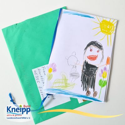 Eine von Kinderhand gezeichnete Karte, auf der ein Mann in schwarzer Gewandung unter einer strahlenden Sonne zu sehen ist. Es handelt sich um Sebastian Kneipp.