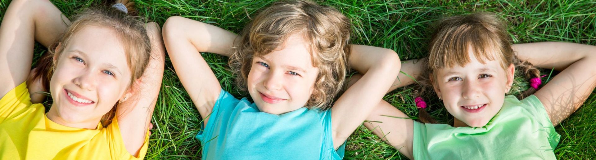 Drei glückliche Kinder liegen im Gras